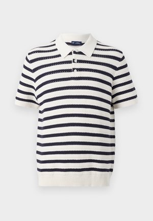 Stribet polo med marineblå og cremefarvede skiftende striber, korte ærmer, ribbet krave og tre-knaps lukning. Strikket tekstur.