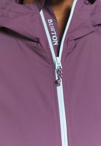 Chaqueta Burton con cierre de cremallera, hecha de tela morada suave, con cremallera y costuras de color azul claro, con capucha y cordón ajustable.