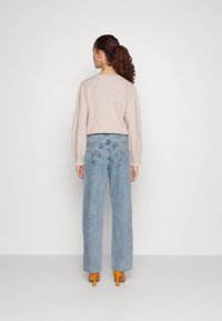 Lys grå genser med puffede ermer; høyt liv lys blå jeans med rett ben; brukt med gule høye sandaler.