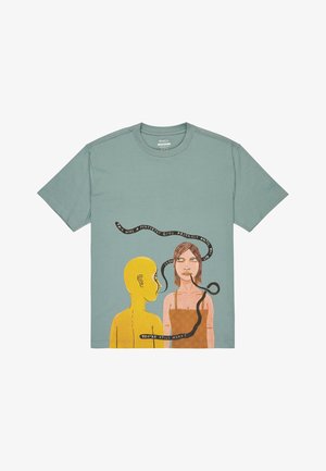 T-shirt in cotone verde menta con stampa astratta di una figura gialla e una donna con nastri testuali, che offre un design grafico e artistico.