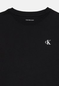 Svart bomulls t-skjorte med rund hals, korte ermer og en liten hvit "cK" logo på venstre brystområde.