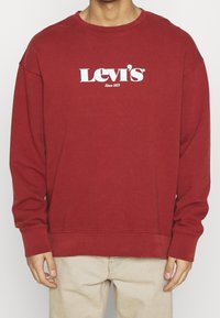 Felpa rossa in cotone, con collo a giro e maniche lunghe. Presenta un logo "Levi's" bianco con la scritta "Since 1873".