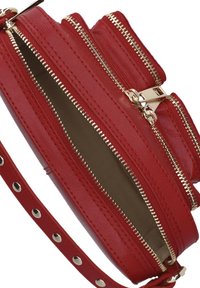 Rode neplederen tas met meerdere ritscompartimenten en goudkleurige hardware. Heeft een gestructureerd oppervlak en een afneembare strap met studs.