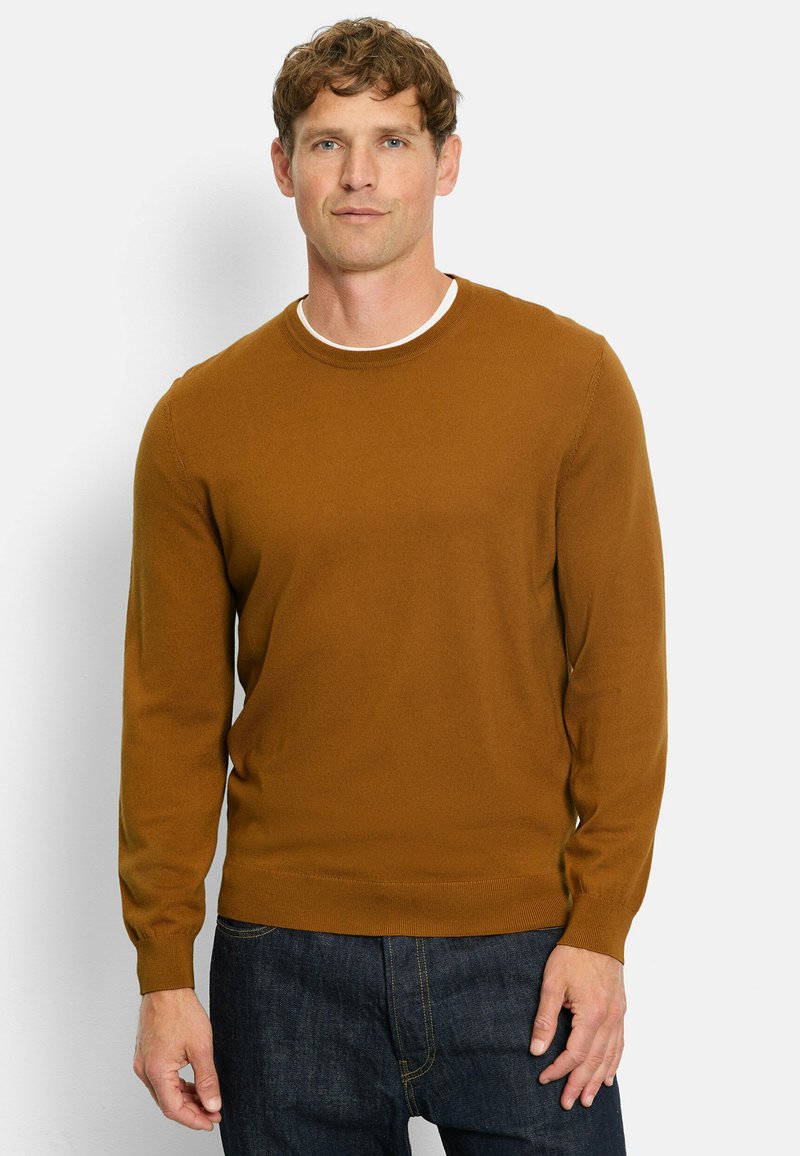 Brauner Strickpullover mit langen Ärmeln, Rundhalsausschnitt, glatter Textur und gerippten Bündchen. Über dunklen Jeans getragen, vor einem neutralen Hintergrund präsentiert.