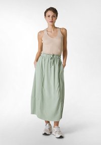 Gonna ankle-length verde chiaro con vita elastica e lacci. Abbinata a una canotta beige a coste e sneakers bianche con accenti grigi.