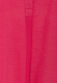 Tessuto rosa con una superficie liscia, caratterizzato da una cucitura verticale e una leggera lucentezza, che crea un design semplice e pulito.