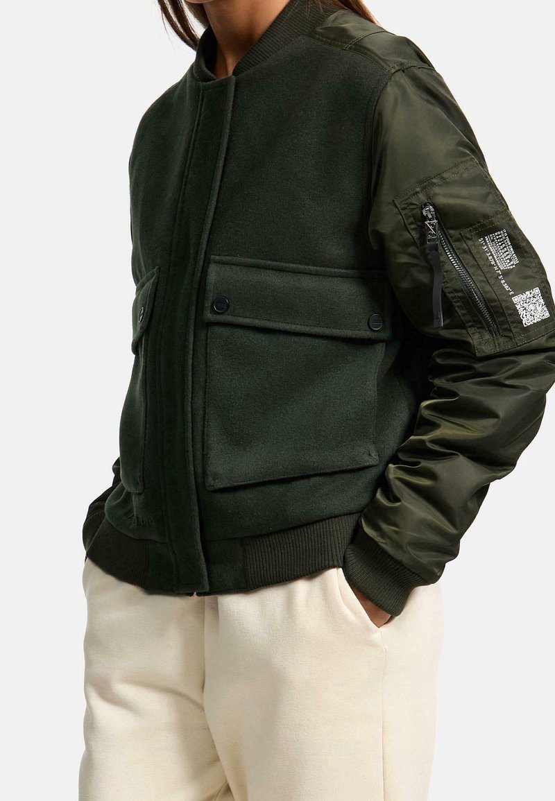 Groene bomberjack met een wol-mix lichaam, nylon mouwen, twee voorzakken, ribgebreide manchetten en een ritstas op de linker mouw.