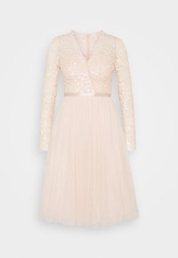 Abito a maniche lunghe, sottogeni, di lunghezza al ginocchio in rosa pallido con bustier di paillettes, scollatura a V e gonna in tulle. Presenta una fascia in vita e una cerniera sul retro.