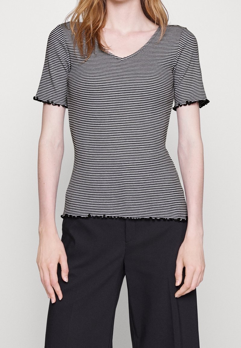 Black and white striped short-sleeve top with a V-neck and ruffled edges, fitted design, made of soft fabric. Paired with black pants.