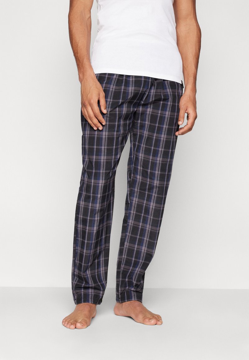 Pantaloni de pijama din bumbac cu carouri în nuanțe de bleumarin și gri, având o croială lejeră, o talie elastică și buzunare laterale, expuși pe picioare goale.