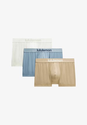 Drie paar herenboxers in beige, blauw en wit met "lululemon"-merkbandjes, overlappend gerangschikt.