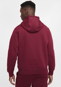 Sudadera color marrón con capucha ajustable, puños y dobladillo acanalados. Material suave con una textura lisa. Detalle de costura visible en la capucha.