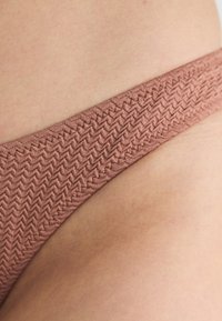 Rudas zigzaginės raštas, sudarantis siaurą juostelę. Minkšta tekstūra su lygiu paviršiumi, skirtas bikini apačiai.