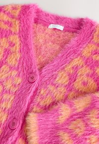 Rosa fluffy cardigan med orange leopardprint, der har V-udskæring, to rosa knapper og blødt, tekstureret materiale. Mærkeetiket synlig.