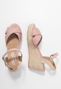 Růžové espadrilové sandály na klínu s křížovými popruhy, textilním svrškem a tkanou juty podrážkou. Obsahují nastavitelné zapínání na kotníku a polstrovanou stélku.