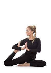 Svart långärmad topp och leggings på en person som utför en yogaposition. Håret är i en flätad hästsvans. Slät hudtextur, neutral bakgrund.
