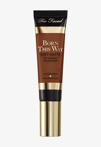 Tube marron de la fondation Too Faced Born This Way Soft Matte Oil Control avec des accents dorés et un bouchon noir. Texte : "Durée de 24 heures" et "Acide Hyaluronique."