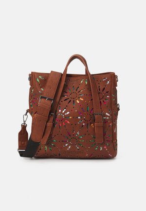 Sac à main en faux cuir marron avec motif découpé floral, accents métalliques, double anses et bandoulière ajustable. Fini texturé.