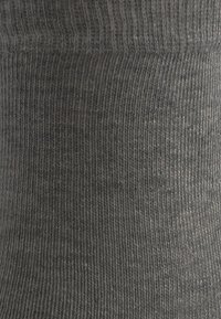 Calza grigia caratterizzata da una texture in maglia elastica con leggere variazioni di tonalità, progettata per comfort e vestibilità.