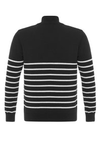 Maglione nero con strisce orizzontali bianche sulla parte bassa della schiena e sulle maniche, dotato di un collo alto e polsini a coste.