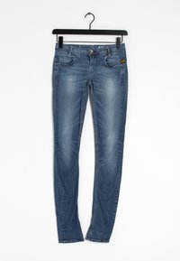 Kapeat farkut keskipitkä sinisen denimkankaan sävyssä, jossa on kulumaa. Ominaisuuksiin kuuluvat viisi taskua, etunappikiinnitys ja vyölenkit. Standardi helman viimeistely.