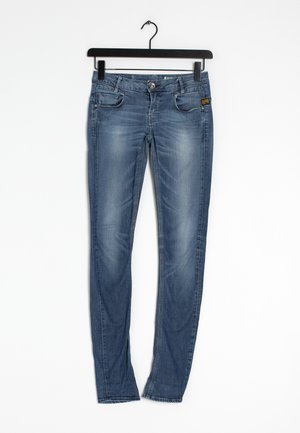 Jeans ajustados en denim azul medio con desgastes. Cuenta con cinco bolsillos, cierre frontal de botón y trabillas para cinturón. Acabado estándar en el dobladillo.