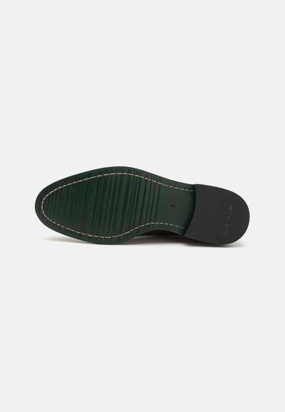 Semelle en cuir vert avec des rainures et des coutures contrastées, dotée d'un capuchon de talon noir. Le dessous affiche un logo et une indication de taille.