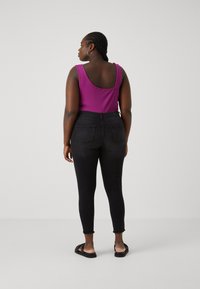 Fitted, solid purple tank top with wide straps paired with high-waisted black skinny jeans featuring back pockets and frayed hems. Black sandals.