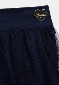 Navy Tüllrock aus strukturiertem Netzstoff mit einem glatten Bund, der mit einem herzförmigen silbernen Hardware-Detail mit "Guess"-Gravur versehen ist.