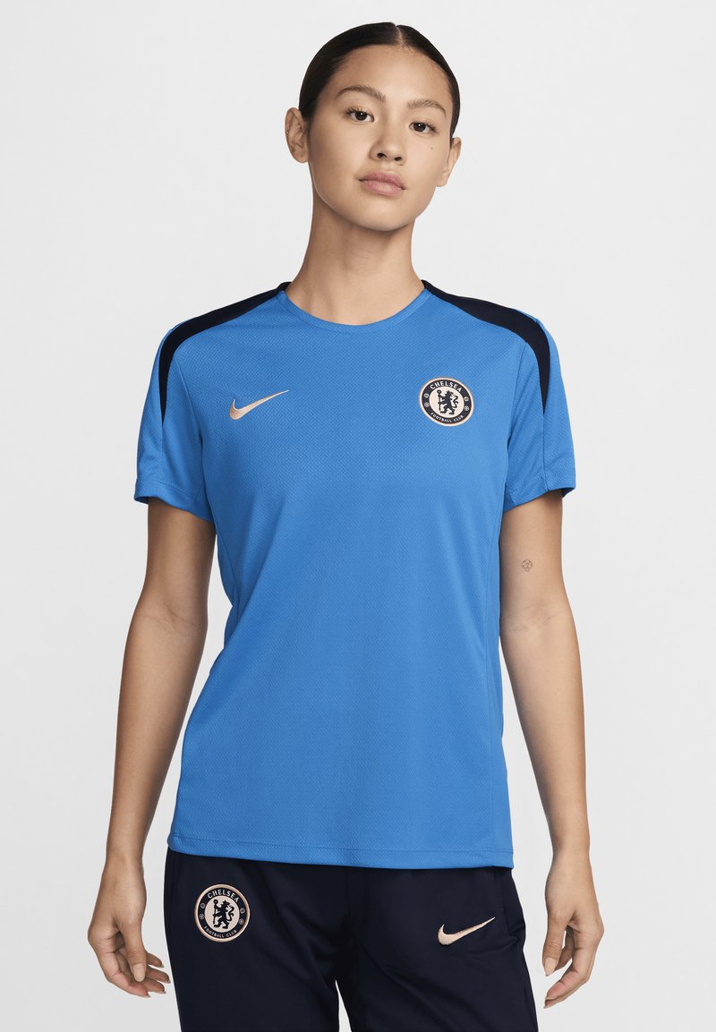 Le maillot bleu Nike du Chelsea FC présente un col rond, des accents noirs sur les épaules et un logo de l'équipe sur la poitrine. Tissu léger texturé.