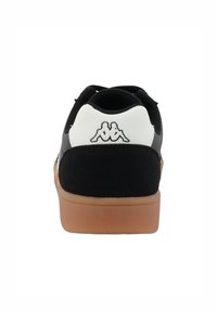 Črno-beli superge z usnjenim in gumijastim dizajnom, s svetlo rjavim gumijastim podplatom in izrazitim logotipom na nagibu pete.