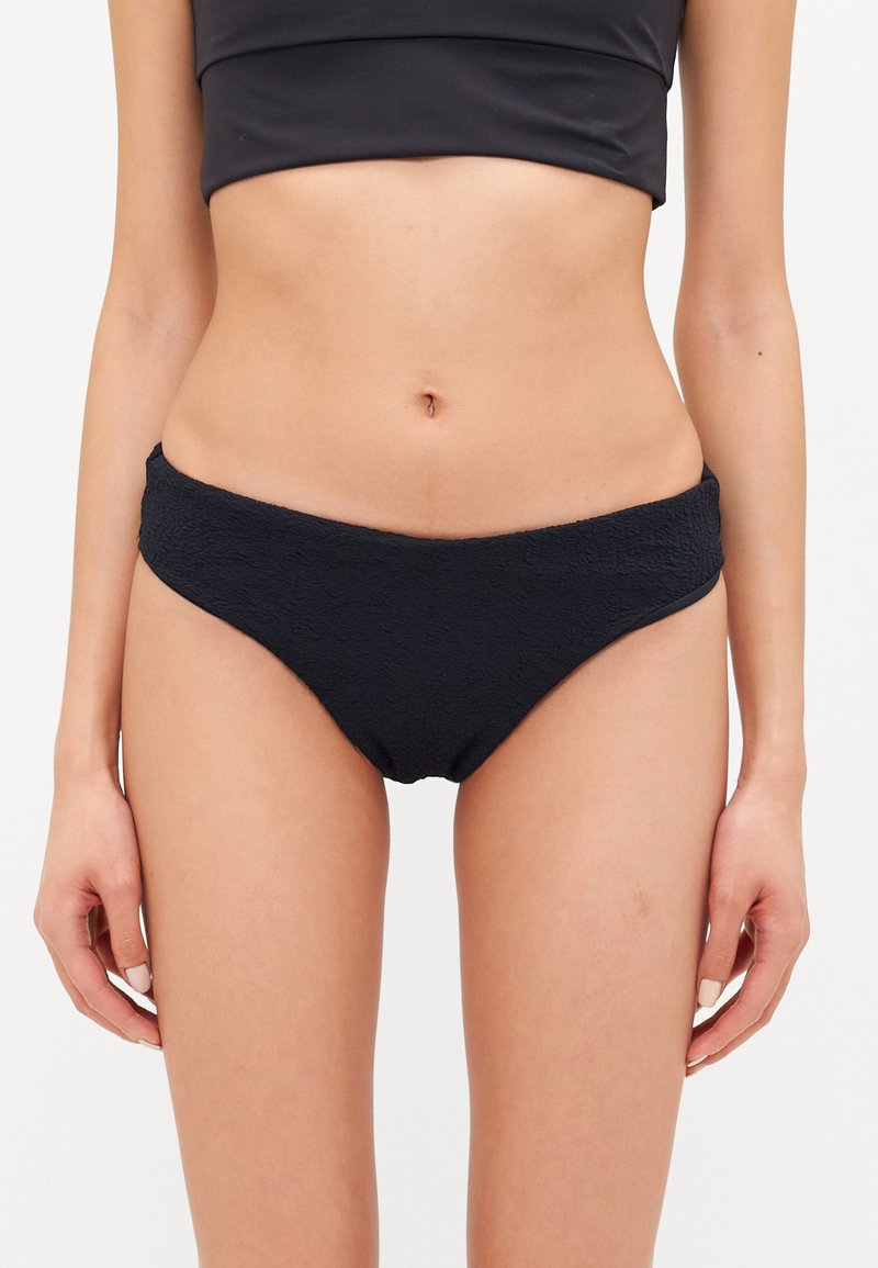 Melnas bikini apakšdaļas ar teksturētu audumu un vidēju pieaugumu, ar plašu jostasvietu komfortam un gludu apdari.