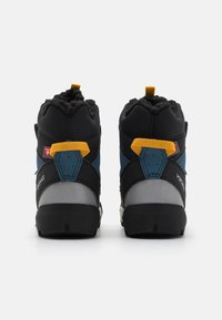 Melnas un zils pusaugstās pārgājienu kurpes ar teksturētu auduma virsu, dzelteniem akcentiem un izturīgu gumijas zoli. Aizmugurējais cilpiņas dizains vieglai uzvilkšanai.
