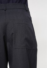 Mörkblå byxor med texturerad yta, med en bakficka, skräddarsydd midja och en stilren design. Minimalistiska med rena linjer.