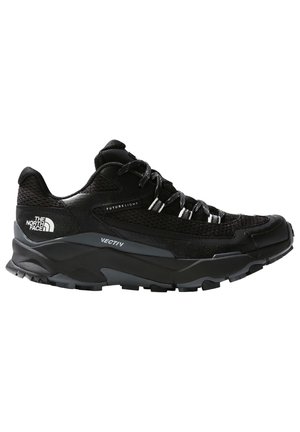 Chaussure de trail running noire avec une tige en mesh, des accents réfléchissants, une semelle en caoutchouc épaisse et un talon renforcé. Équipée d'un système de lacets sécurisé.