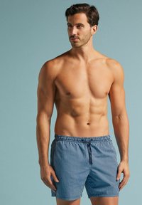 Bañador a rayas azul y blanco con cintura elástica y cordón. La tela parece ligera y suave con un corte relajado.