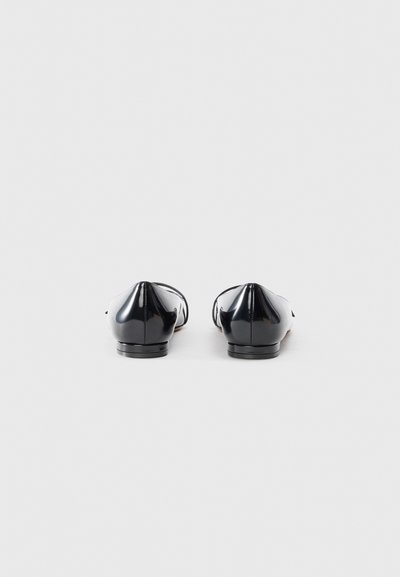 Black patent leather flats with a rounded toe and low heel. Simple design with minimal detailing and a smooth, shiny texture.