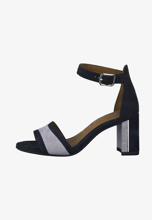 Czarno-szare zamszowe sandały na obcasie z paskiem wokół kostki, otwartym noskiem i słupkowym obcasem z metalicznym akcentem. Teksturowany wzór paska.