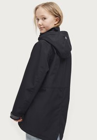 Zwarte waterdichte jas met een capuchon, met een relaxed fit, lange mouwen en verstelbare manchetten, weergegeven vanuit een lichte achteraanzicht.