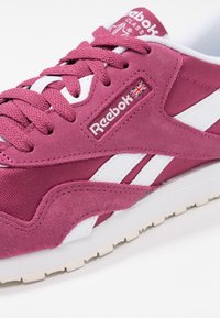 Reebok klasické tenisky v tmavě růžové semišové a síťované úpravě, se světlými akcentními pruhy, texturovanými tkaničkami a logem na jazyku.