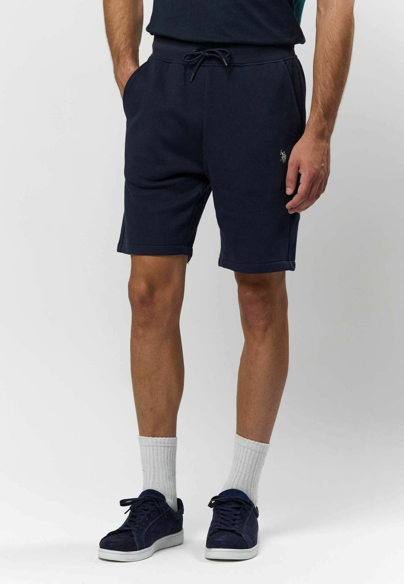 Shorts de survêtement bleu marine avec une taille élastique et un cordon de serrage, dotés de poches latérales et d'un petit logo sur la cuisse gauche.