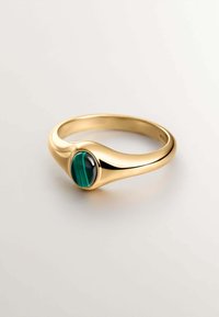 Anillo de oro con una banda lisa y una prominente piedra ovalada de malaquita con franjas de color verde oscuro y negro. Diseño elegante y minimalista.