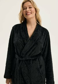 Czarny pluszowy szlafrok z teksturowanym wzorem w diamenty, z długimi rękawami, kołnierzem szalowym oraz dopasowanym paskiem do zapięcia.