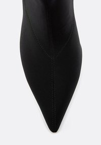 Črne gležnjarje s pointe, izdelane iz gladkega blaga; imajo vidne šive ob šivu za strukturo in oblikovne podrobnosti.