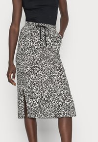 Czarna i biała spódnica midi w wzory, z elastycznym paskiem, troczkiem i rozcięciem z boku. Wykonana z lekkiego materiału.