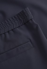 Pantalones cortos de tela azul marino con una textura suave, cinturilla elástica fruncida y un pequeño logo "GABBA" en tonalidad bordado en el costado.