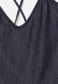 Tissu en denim bleu foncé avec un décolleté en V et de fines bretelles croisées dans le dos d’un vêtement.
