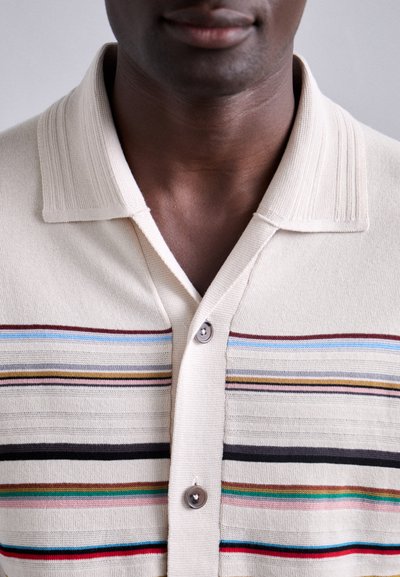 Beige overhemd met kraag en horizontale meerkleurige strepen, voorzien van twee knopen en een gestructureerde ribbelkraag. Zachte stoftextuur.