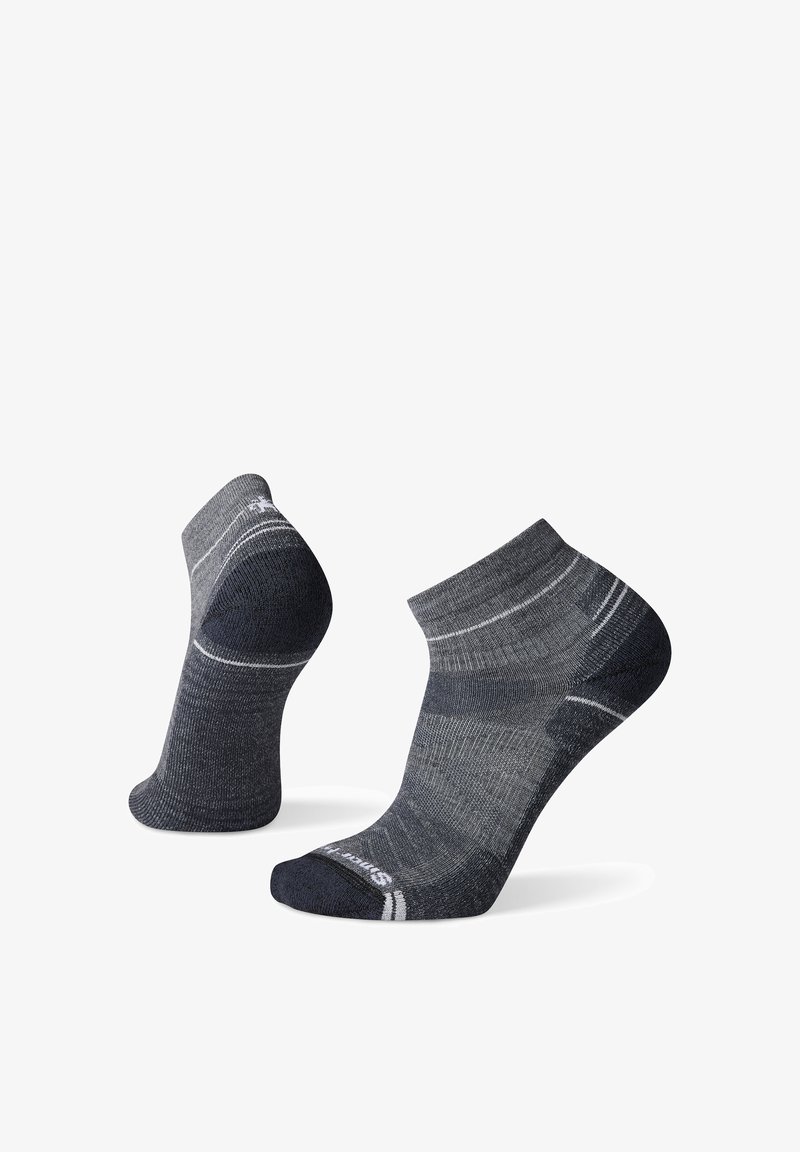 Paar dunkelgraue und schwarze Knöchelsocken mit hellgrauen Streifen und gepolsterten Fersen und Zehen vor weißem Hintergrund.