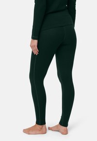 Dunkelgrüne Leggings aus weichem, dehnbarem Material; mit kontrastierenden hellen Nähten, schlanker Passform und hohem Bund.